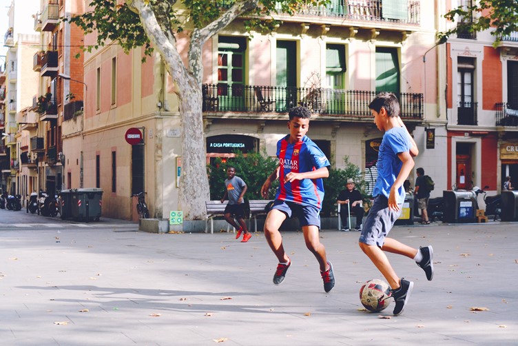 two kids playing football in the street