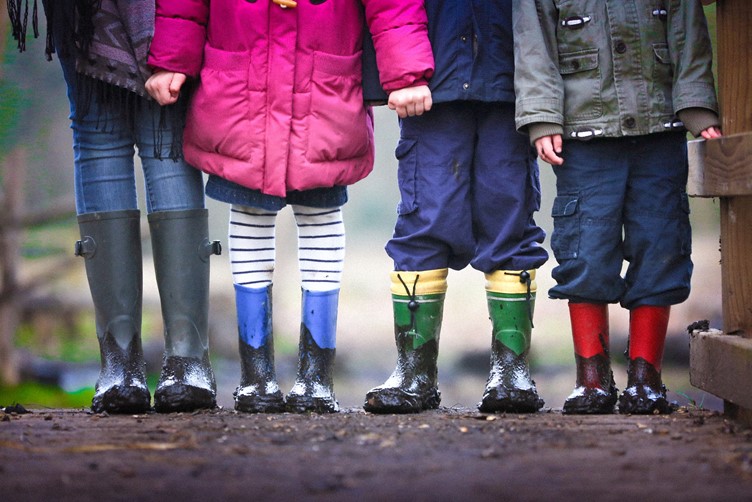 Four kids standing in a line, in wellington boots