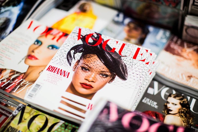 A vogue magazine with the picture of celebrity Rihanna on the front cover, placed on a table with other magazines